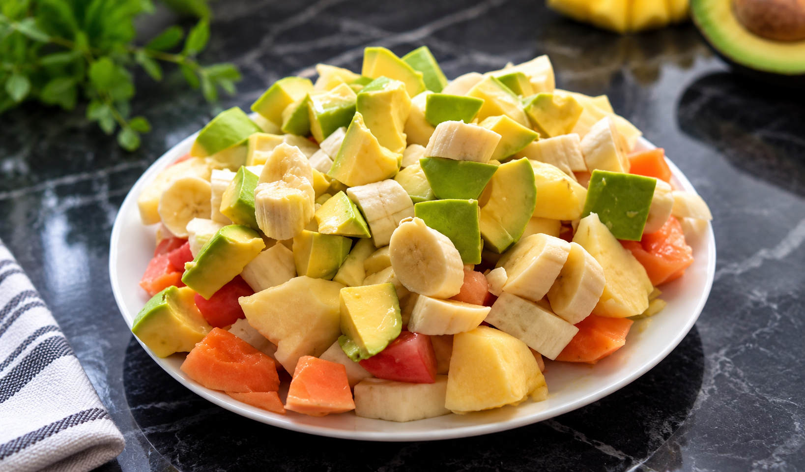Plate of diced ripe avocado, banana and mixed seasonal fruit