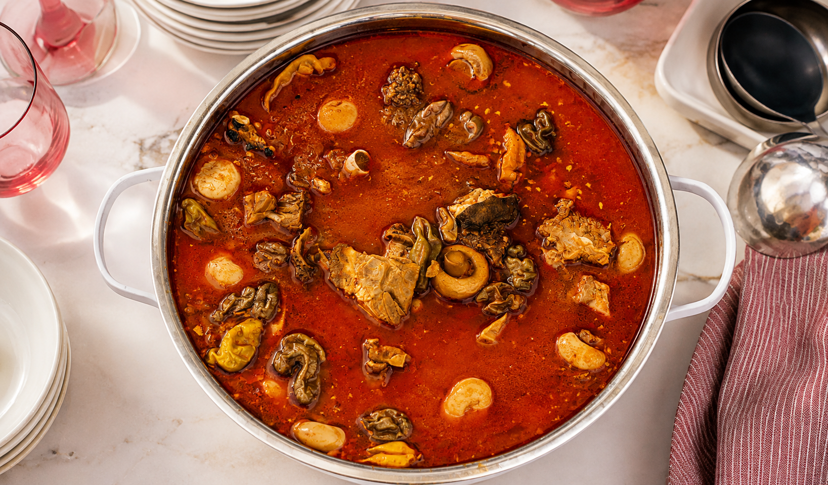 Large pot of spicy red pepper soup with assorted goat meat