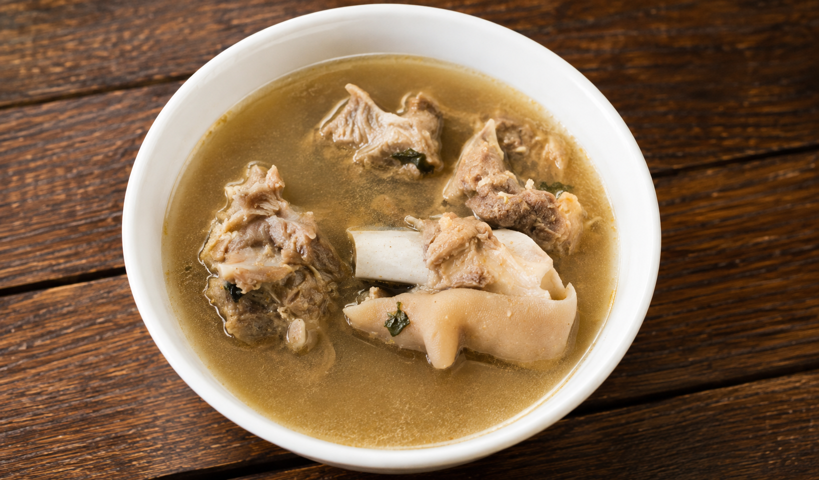 Clear goat-meat pepper soup with tender pieces in a white bowl