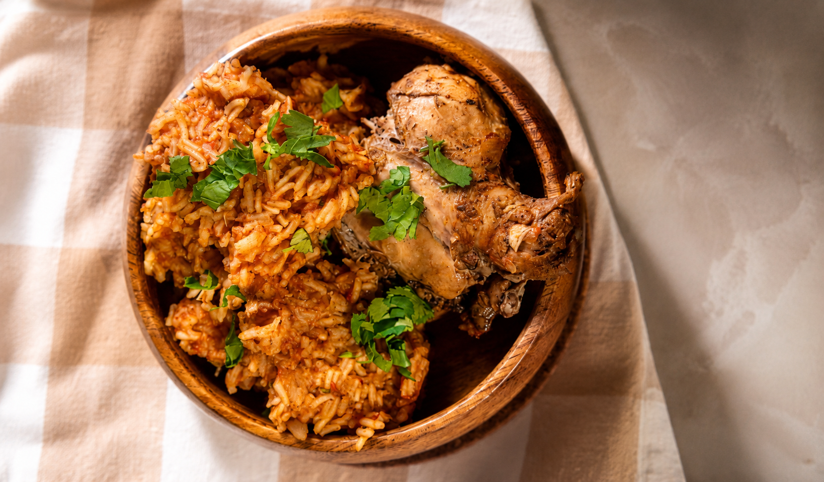 Jollof rice with grilled chicken and parsley in a wooden bowl