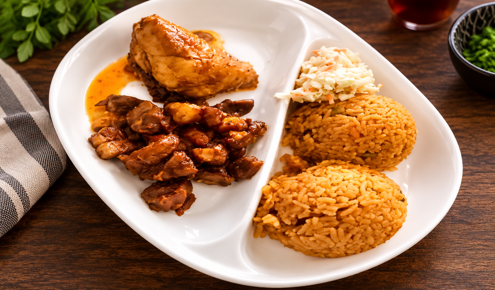 Nigerian plate: jollof rice scoops, fried chicken, diced fried beef and coleslaw on a divided plate